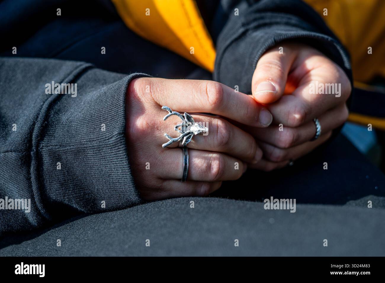 Nahaufnahme gefalteter Hände mit markanten Silberringen im Freien. Stockfoto