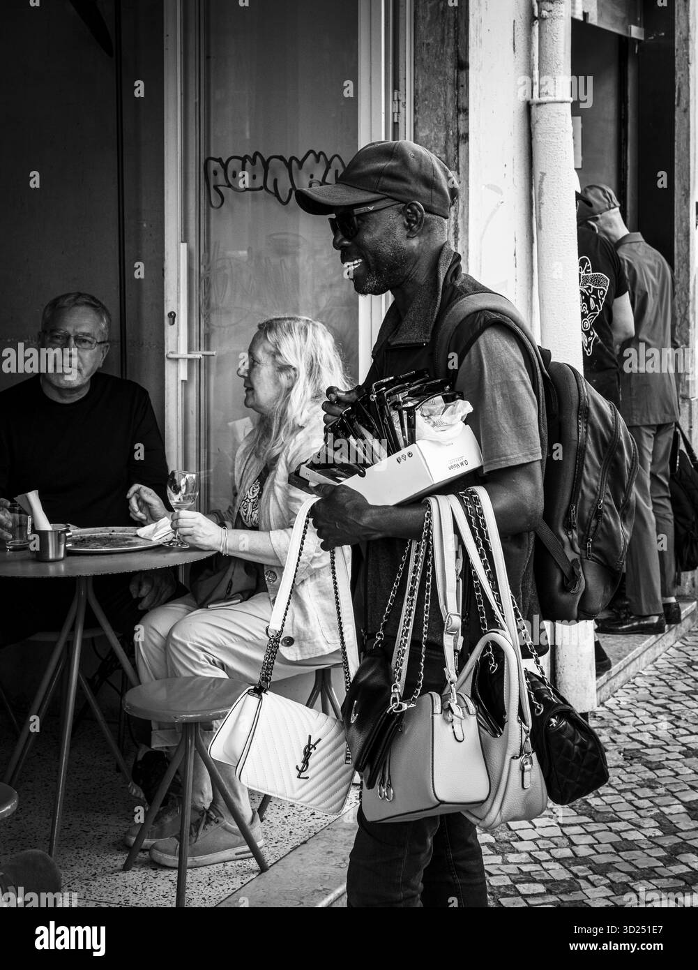 Schwarzweiß-Fotografie, Straßenkunst, Händler, der seine Waren anbietet, Lissabon, Portugal Stockfoto
