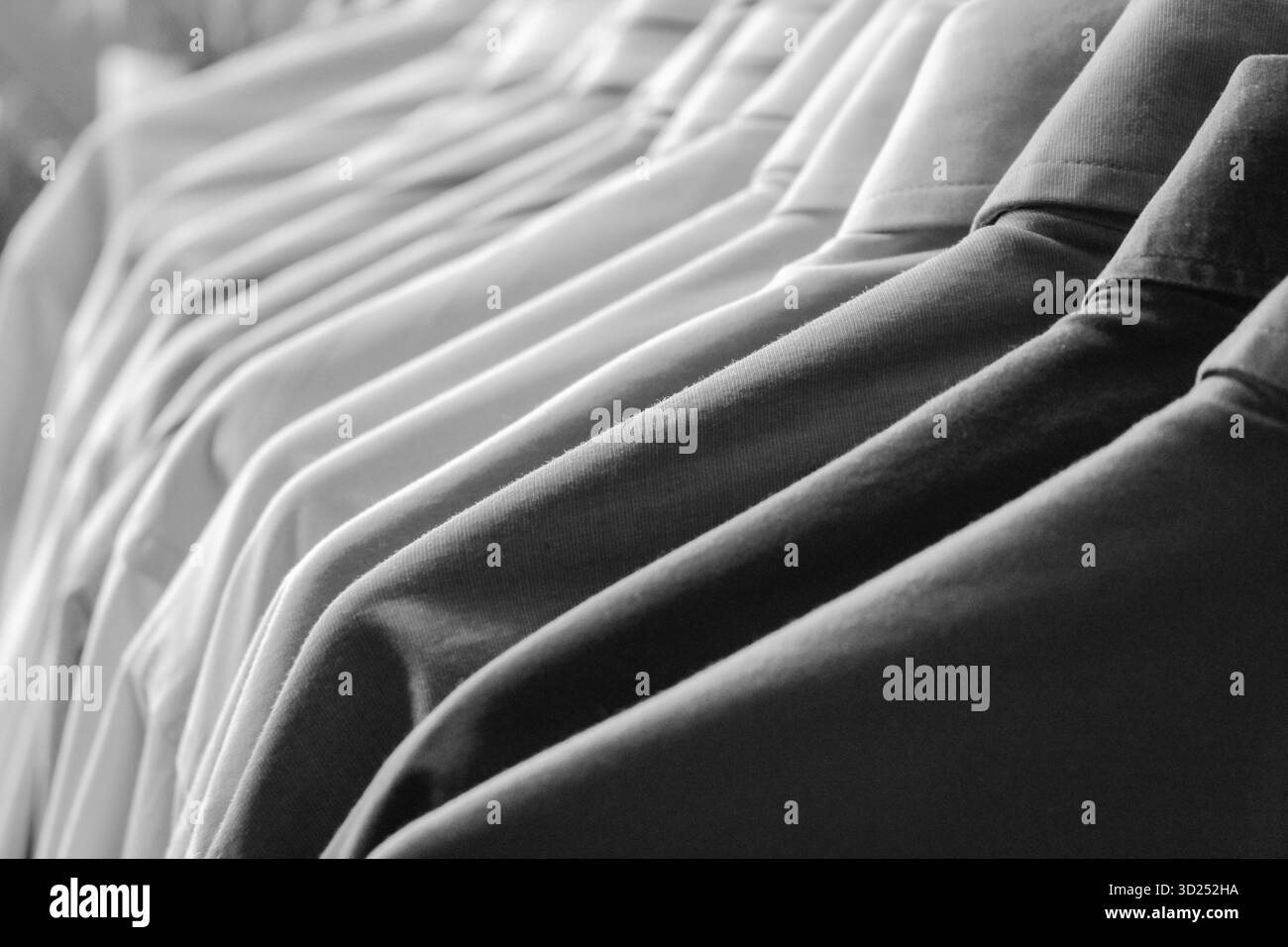 Nahaufnahme von langärmeligen Hemden mit Knopfverschluss und Kragen in einem Reihenschrank. Professionelle Kleidung Kleidung Hintergrund. Stockfoto