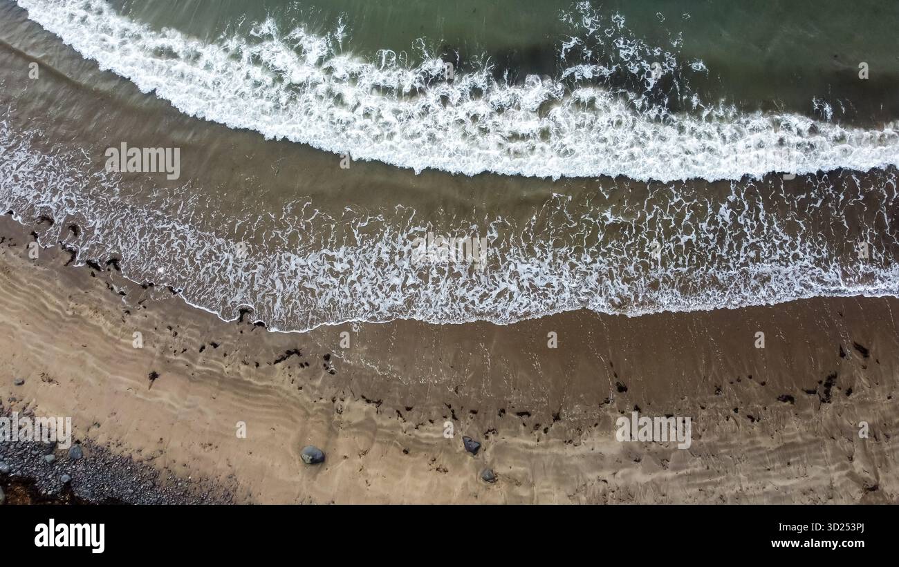Aus der Vogelperspektive der Meereswellen, die auf eine Sandküste Rollen Stockfoto