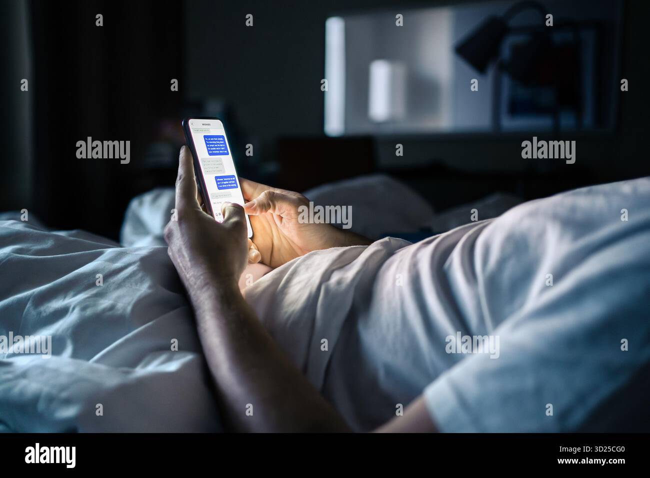 Telefon im Bett. Textnachricht. Mann-SMS. Bildschirmzeit in der Nacht. Verwenden der Smartphone Messenger-App in einem dunklen Schlafzimmer oder Hotelzimmer vor dem Schlafen. Stockfoto