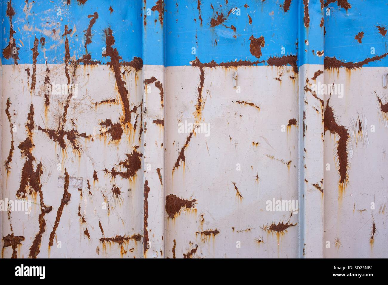 Rost und abblätternde Farbe auf einem blau-weißen Metallbehälter Stockfoto