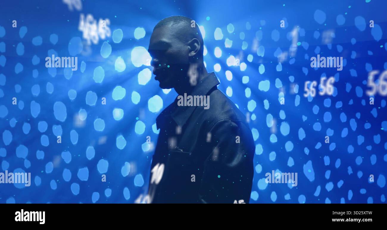 Stehender Mann in dunkler Jacke in dunklem Studio, mit blauen Bokeh-Lichtern und numerischen Projektionen Stockfoto