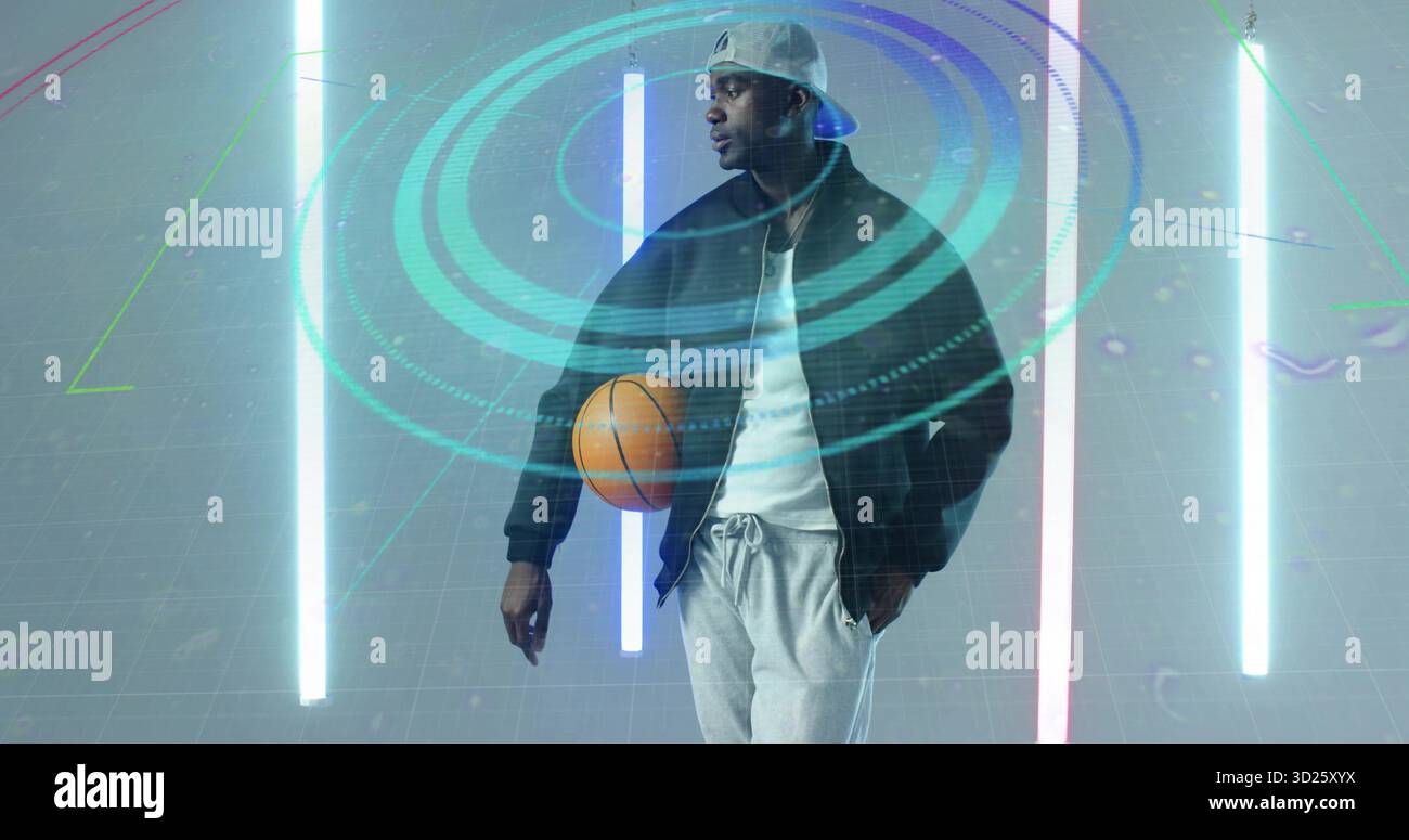Positiver männlicher Athlet in Sportbekleidung, der orangener Basketball im Technikstudio hält, mit Hologrammringen Stockfoto