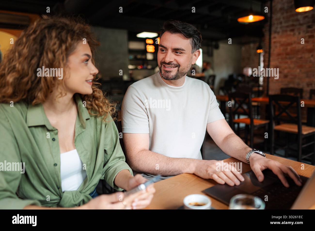 Ein junges Paar, das an Laptop arbeitet und im Café diskutiert Stockfoto