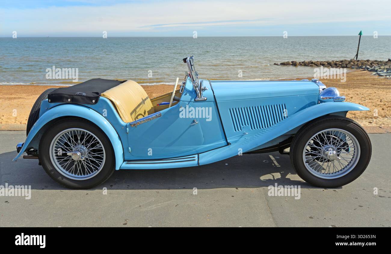 Klassischer hellblauer MG Roadster parkte an der Strandpromenade Strand und Meer im Hintergrund Stockfoto