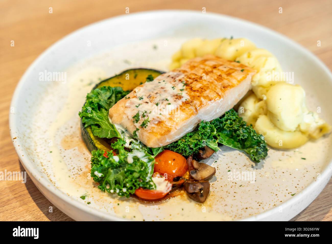 Leckeres gegrilltes Lachssteak mit Gemüse und Kartoffelpüree, serviert auf hellem Holztisch, Nahaufnahme. Stockfoto