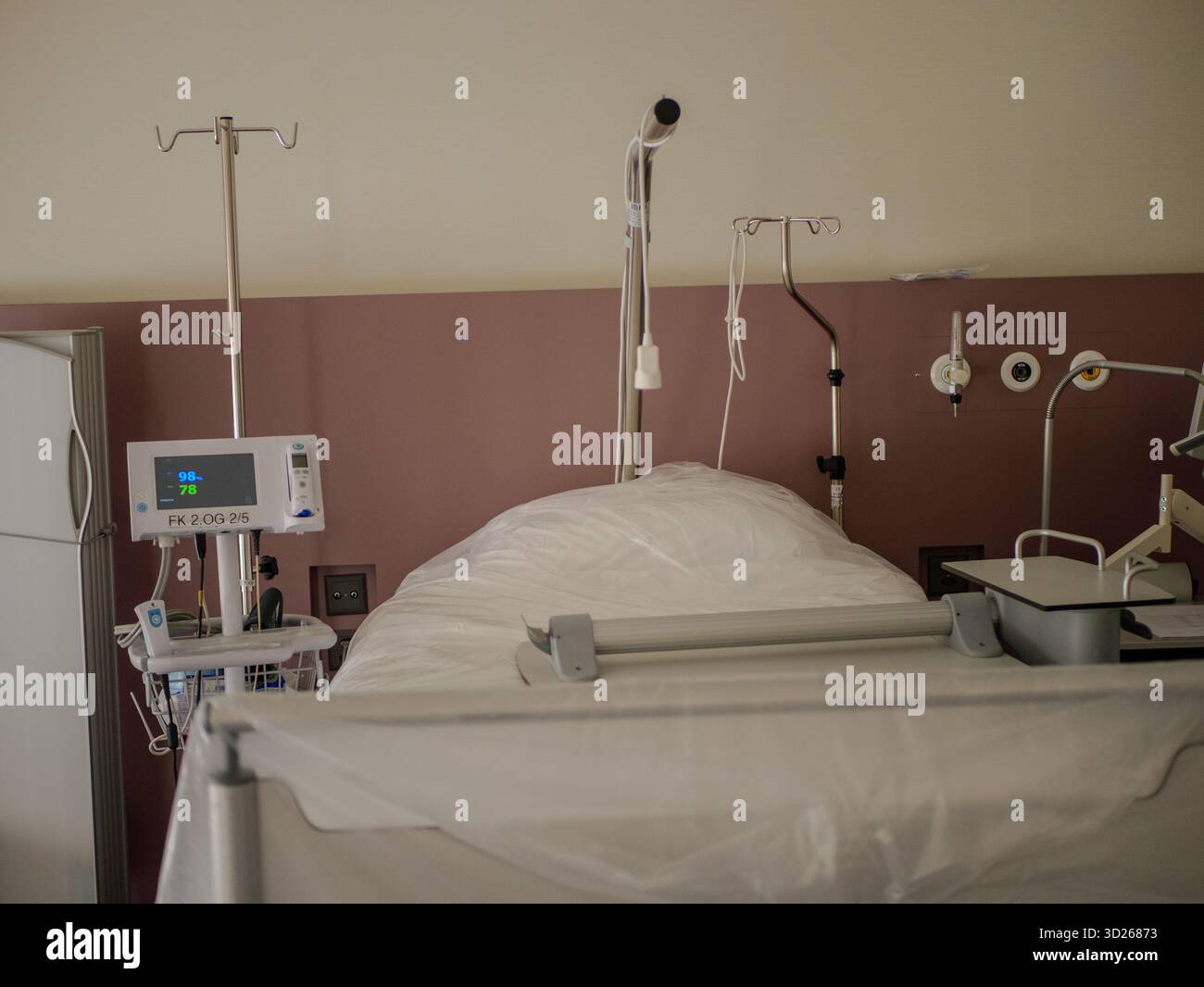 Krankenhausbett mit medizinischem Monitor und Infusionsständer im modernen Aufwachraum, Gesundheits- und Patientenbehandlungsgeräte im klinischen Umfeld, pro Foto. Stockfoto