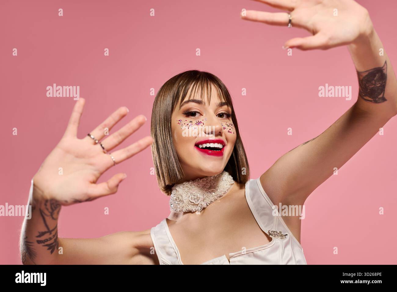 Eine stilvolle junge Frau drückt ihren verspielten Geist mit lebhaften Gesten und auffälligem Make-up aus. Stockfoto