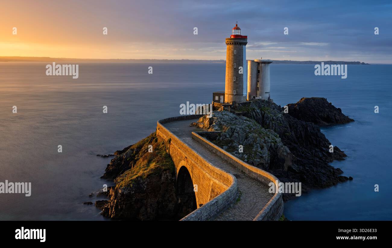 Der Leuchtturm Phare du Petit Minou steht stolz am felsigen Ufer, wenn die Sonne untergeht und warme Farbtöne über den Ozean wirft. Die ruhige Atmosphäre ist enha Stockfoto