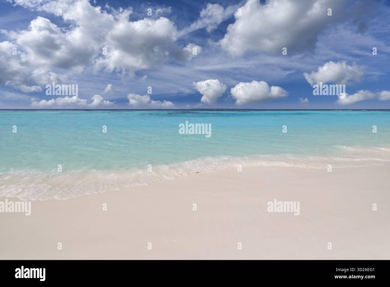 Entspannender weißer Sandstrand mit friedlichen Wellen, sonnigem Ozeanhorizont, inspirierender Sommer-Natur-Hintergrund Stockfoto