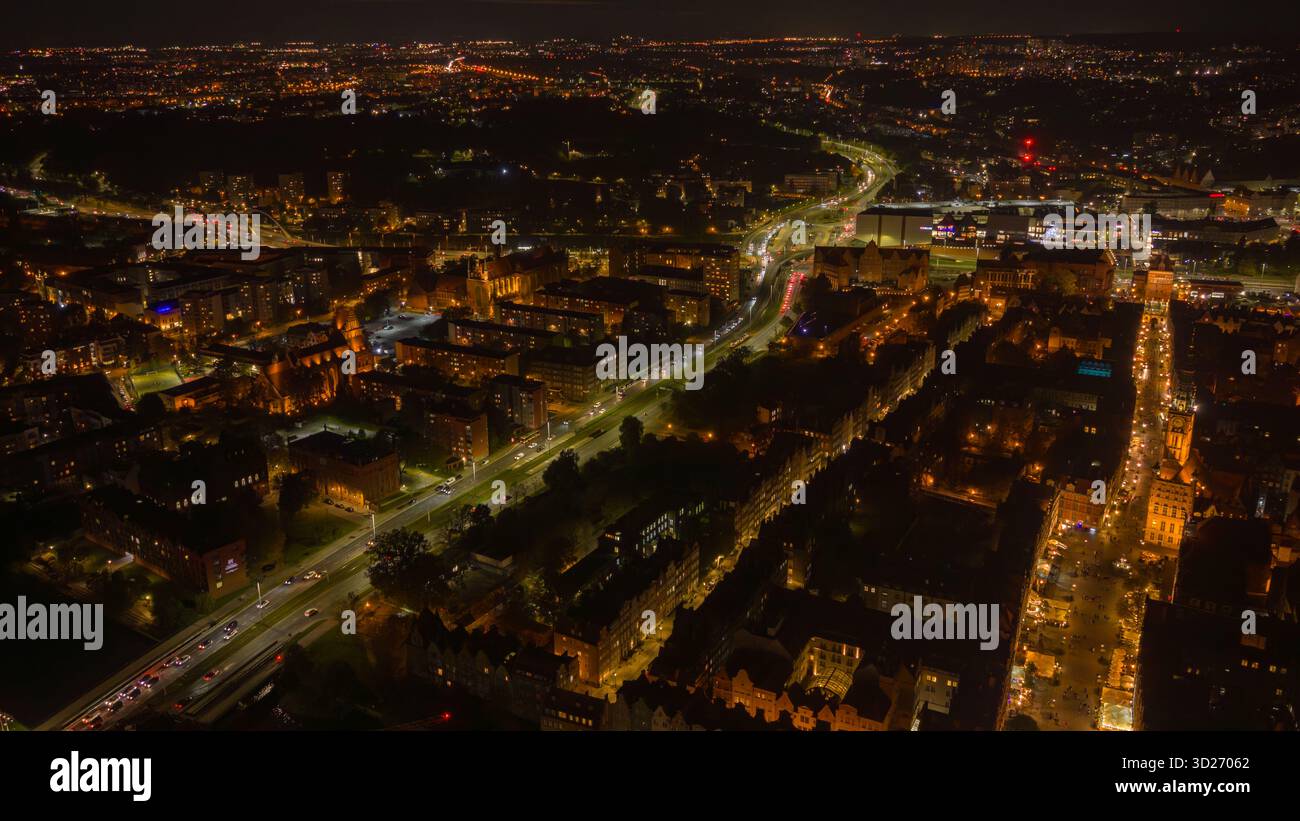 Die Nachtluftfahrt zeigt Danzig, Polen, mit bernsteinfarbenen Lichtern, kurvigem Verkehr in die Altstadt, St. Marys Kirche, Long Market und Motlawa-Reflexionen im tiefen shado Stockfoto