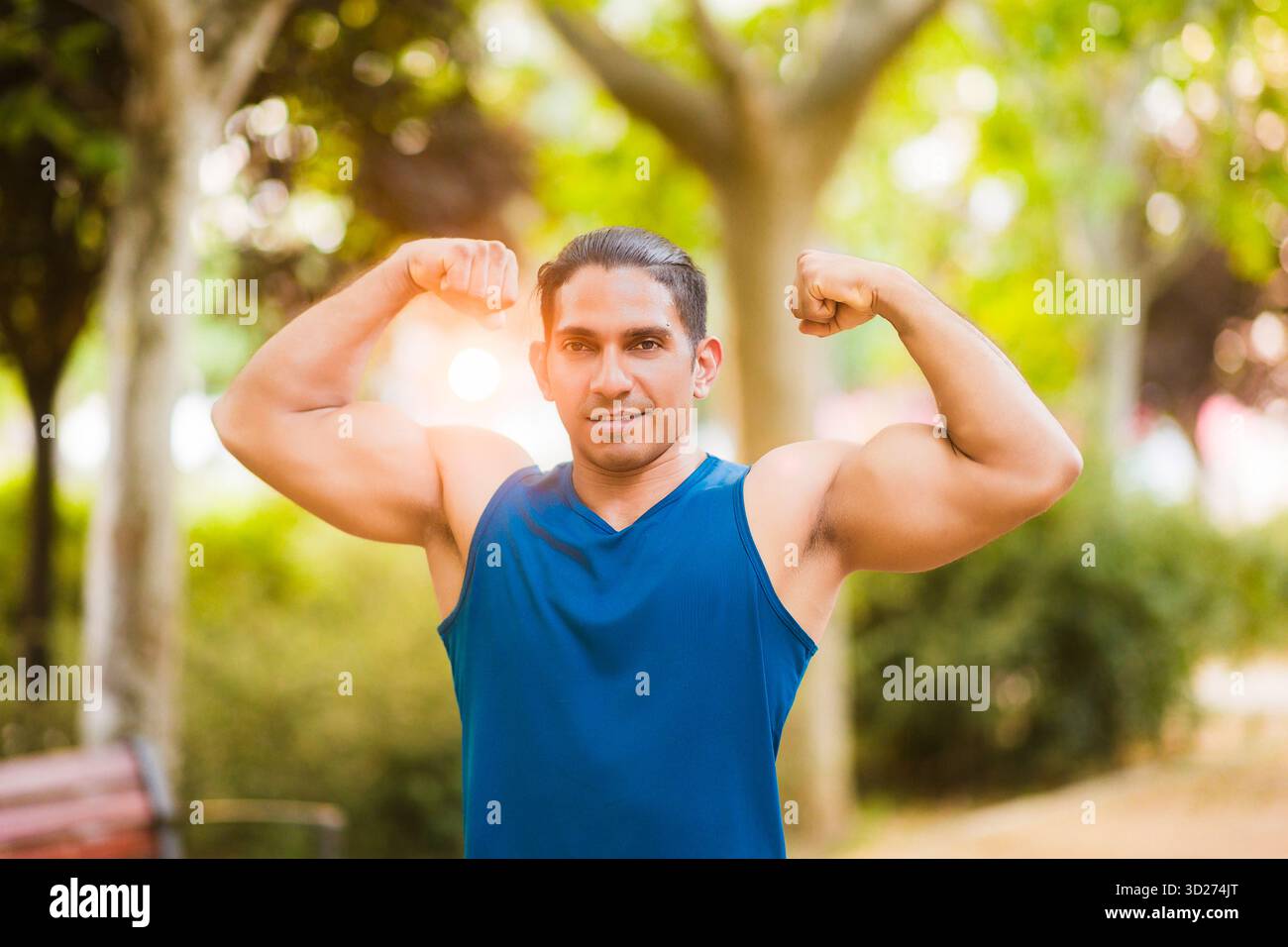 Starker lateinischer Mann, der im Park Muskeln beugt Stockfoto