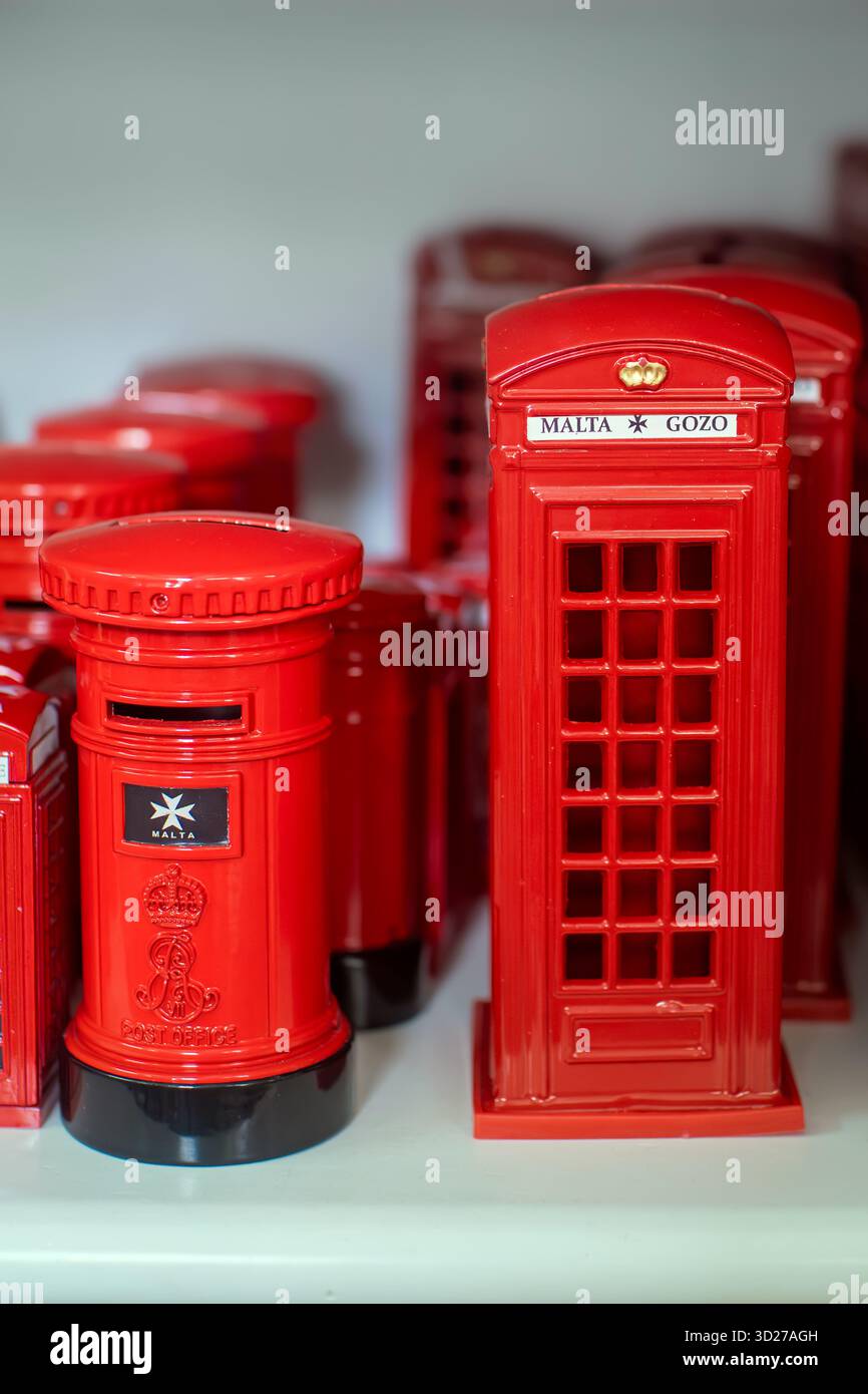 Nahaufnahme von roten maltesischen Souvenirs - ein britischer Sparkastenfach und Telefonzelle mit der Aufschrift Malta und Gozo in einem Ladenregal. Stockfoto