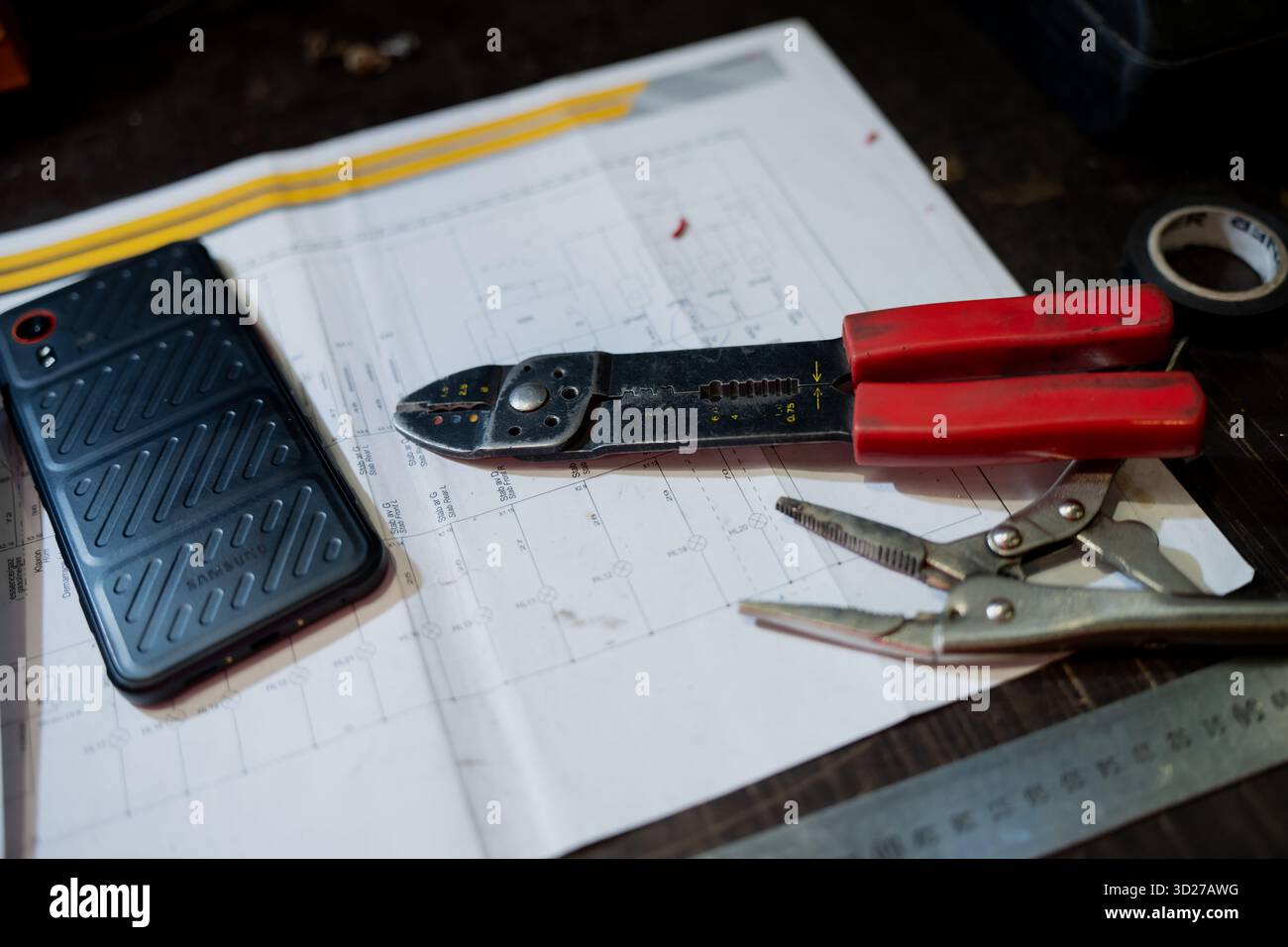 Arbeitsbereich für Elektriker mit Werkzeugen, Telefon- und Verdrahtungskonzept auf dem Schreibtisch für Reparaturarbeiten, Wartungsplanung und moderne technische Vorbereitung Stockfoto