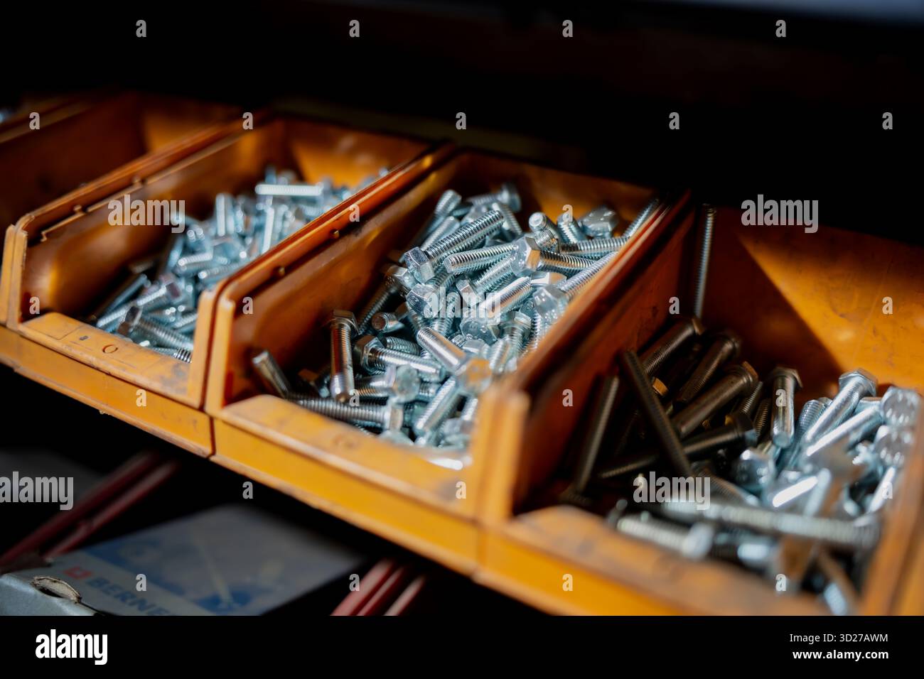 Metallbolzen in gelben Werkstattbehältern mit Präzisionsbefestigungen, Stahlbauteilen und Lagerung von Industriematerial für mechanische AS Stockfoto
