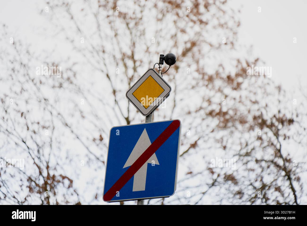 Straßenschilder mit blauem Richtungspfeil, der von einer roten Linie und einem gelben Rautenring überkreuzt wird, der das Ende der Einbahnstraße und der Kreuzung darstellt Stockfoto