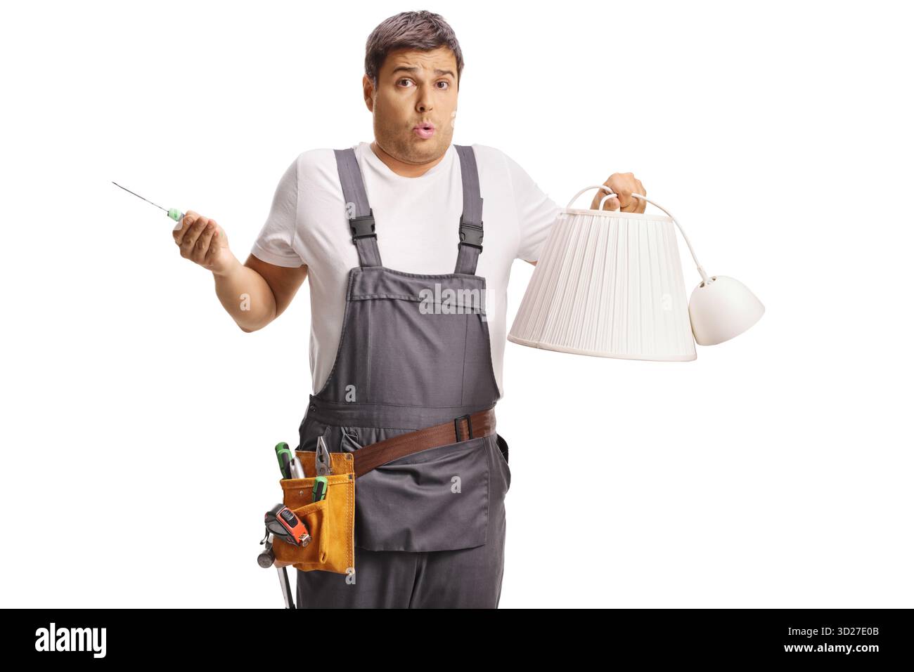 Verwirrter Reparaturmann, der einen Schraubenzieher und einen Lampenschirm auf weißem Hintergrund hält Stockfoto