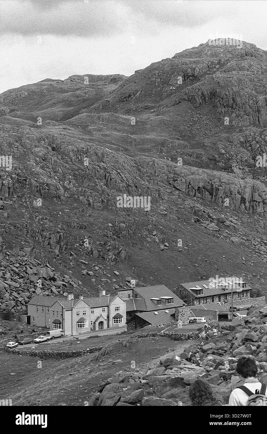 Das Pen y Pass Warden Centre liegt am Fuße des beeindruckenden Tryfan und ist eine wichtige Anlaufstelle für Wanderer, die sich mit der legendären Snowdonia-Reihe auseinandersetzen. Das Zentrum, ein historisches Gebäude, bietet wichtige Einrichtungen wie Unterkunft, Catering, und Vorräte, die den anspruchsvollen Bedürfnissen von Bergsteigern und Wanderer gerecht werden, die das anspruchsvolle Gelände von Nant Gwynant, Caernarfonshire, erkunden. Stockfoto