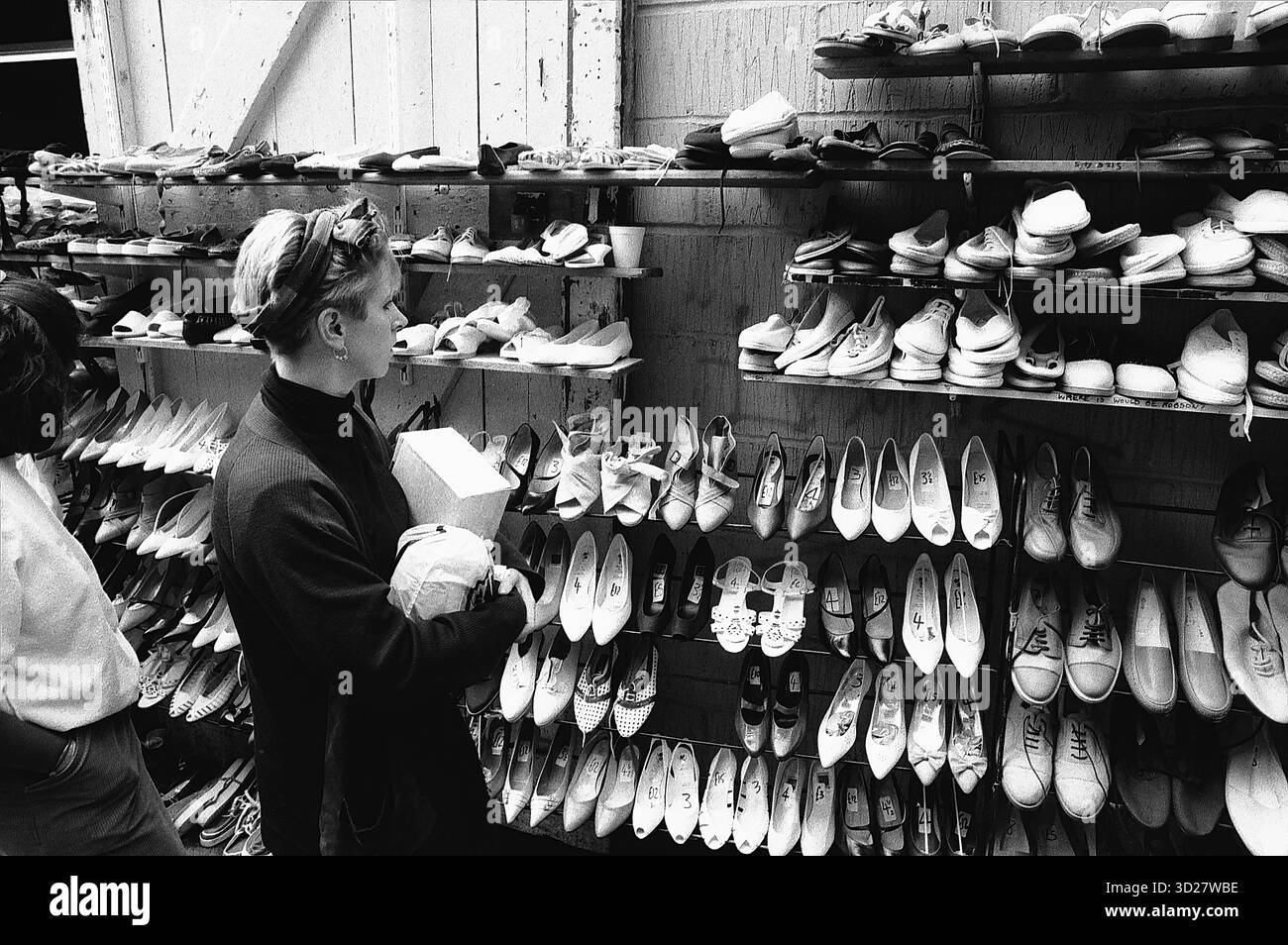 Camden Lock Market: Ein Blick in Londons einzigartige Craft Scene. In der belebten Atmosphäre von Camden Lock präsentiert ein Handwerker seine Schuhkollektion sorgfältig. Der historische Markt am Kanal, ein pulsierendes Zentrum unabhängiger Händler und Kunsthandwerker, bietet einen faszinierenden Einblick in Londons kreativen Geist. Stockfoto