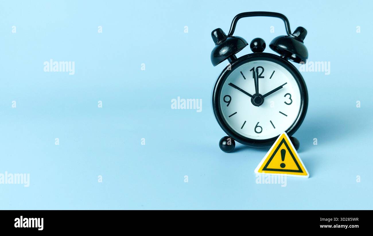 Kritisches Deadline- und Zeitmanagement-Risiko: Warnschild auf schwarzem Wecker Stockfoto