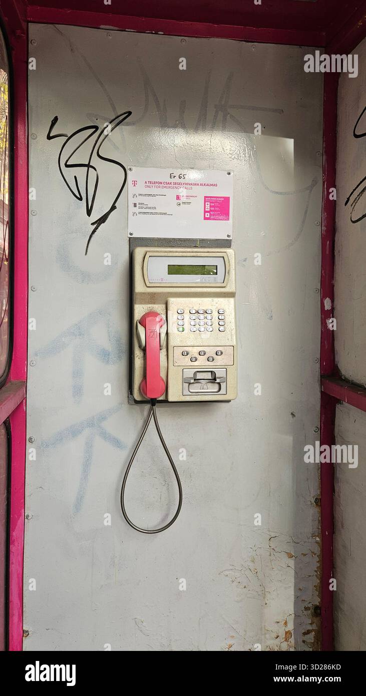 Retro T-Mobile Münztelefon / öffentliches Telefon in einer verwitterten, mit Graffiti bedeckten Telefonzelle in Budapest Stockfoto
