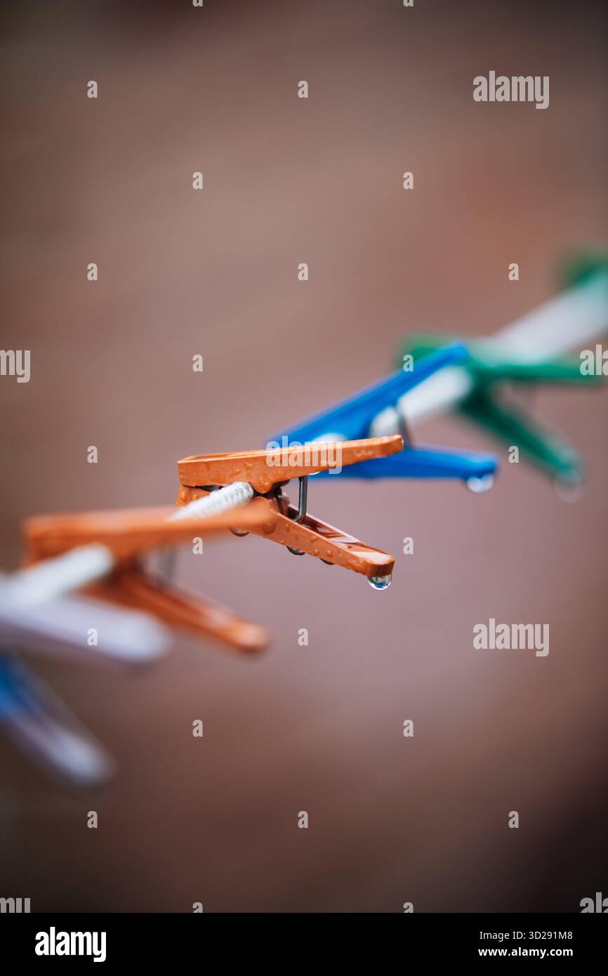 Regentropfen hängen an bunten Kleiderschalen auf einer Wäscheleine Stockfoto
