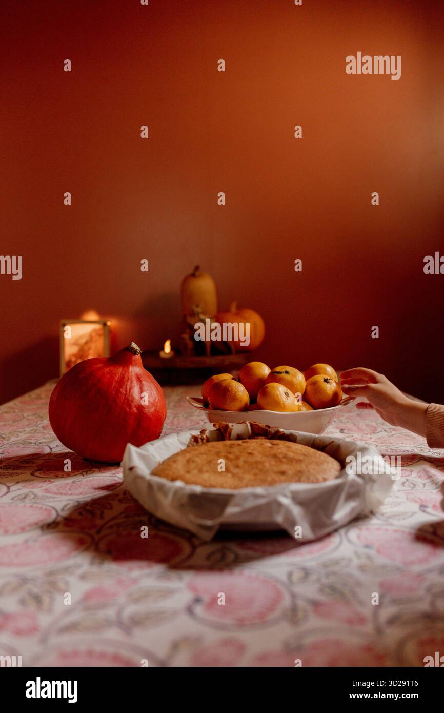 Kind schneidet hausgemachten Kuchen auf gemusterter Tischdecke Stockfoto