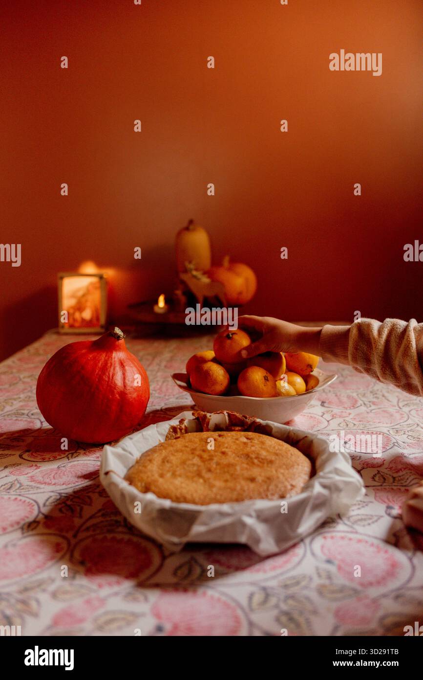 Kind schneidet hausgemachten Kuchen auf gemusterter Tischdecke Stockfoto