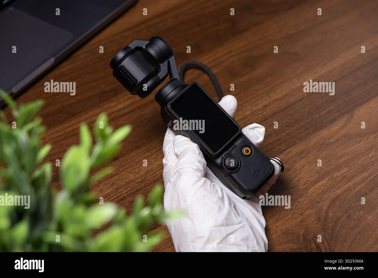 Poznan, Polen – 16. Oktober 2025: DJI Osmo Pocket, eine kompakte schwarze Gimbal-Kamera, die von einer Hand mit Handschuhen gehalten wird, auf einem hölzernen Schreibtisch zum Vloggen und Erstellen Stockfoto