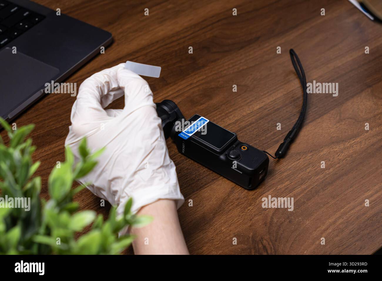 Poznan, Polen – 16. Oktober 2025: Eine Hand mit Handschuhen bringt eine klare Displayschutzfolie auf eine DJI Osmo Pocket Kamera an, um eine ordnungsgemäße Vorrichtung zu gewährleisten Stockfoto