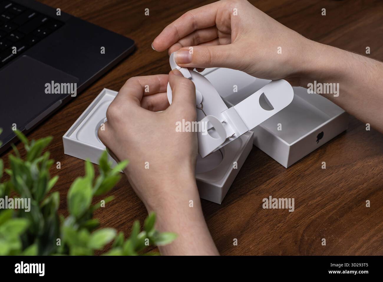 Posen, Polen – 16. Oktober 2025: Top-down-Perspektive menschlicher Hände, die akribisch das weiße Paket eines neu erworbenen Apple Electronic-Produkts öffnen Stockfoto
