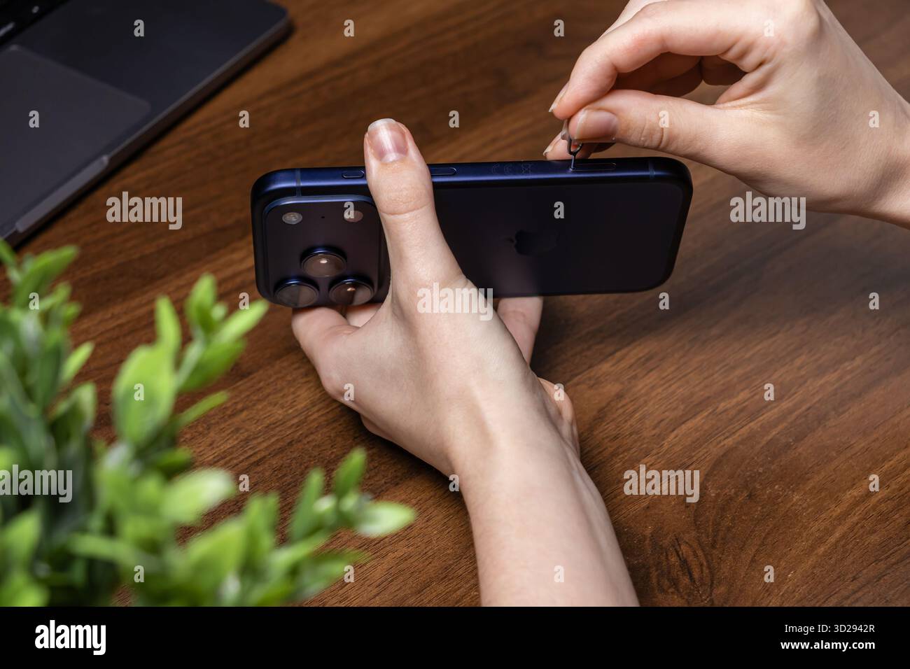 Posen, Polen – 16. Oktober 2025: Hände, die ein SIM-Tool in das dunkelblaue iPhone 17 Pro einlegen, demonstrieren die Einrichtung des Geräts und den wichtigen mobilen Anschluss Stockfoto