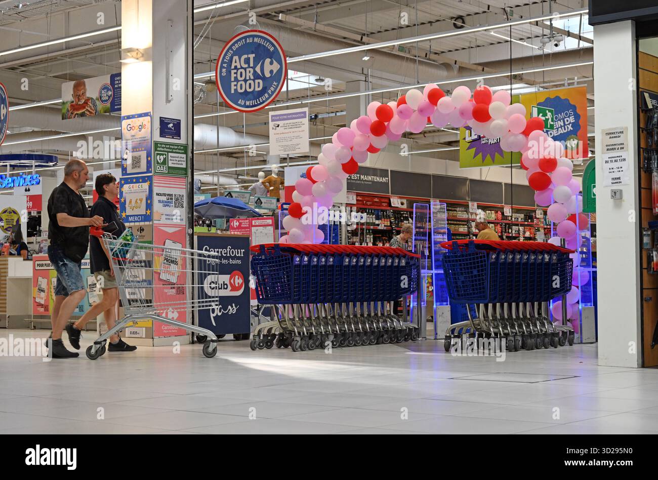 Käufer oder Verbraucher mit Supermarkt-Trolley oder Einkaufswagen, die Carrefour Supermarket France betreten Stockfoto