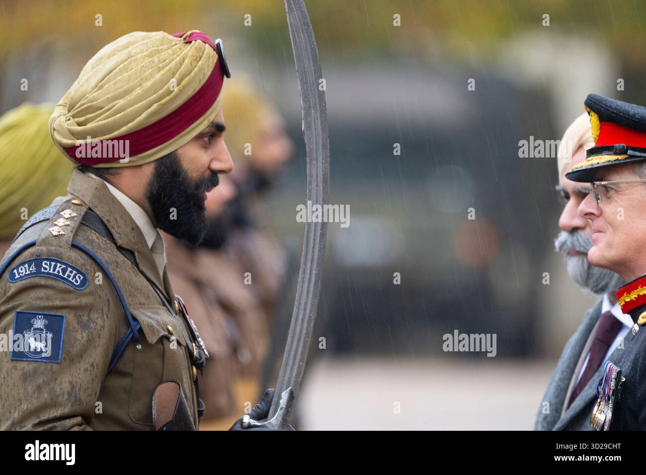 Wellington Barracks, London, Großbritannien. Oktober 2025. 1914 feierliche Einweihung der Sikhs-Marschtruppe, die Tausenden von Sikh-Soldaten gewidmet ist, die im Ersten Weltkrieg und darüber hinaus dienten und in authentischen Sikh-Infanterie-Uniformen des Ersten Weltkriegs gekleidet waren, komplett mit zeitgetreuem Lee-Enfield-Gewehr. Die volle zeremonielle Parade findet bei starkem Regen mit der Band of the Irish Guards statt. Bild: Inspektion der Trooр durch Generalmajor John Kendall (Stellvertretender Befehlshaber der Feldarmee) und Gurpreet Singh Anand. Kredit: Malcolm Park/Alamy Stockfoto