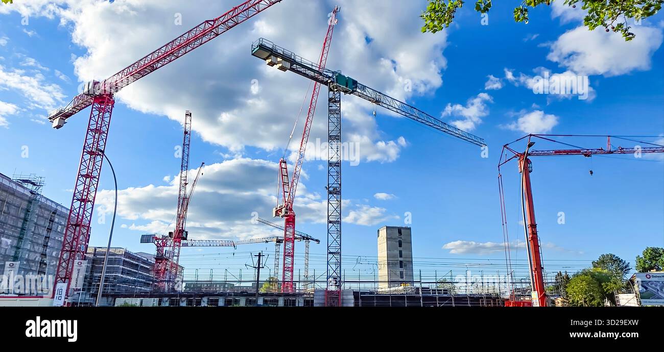 Berlin, Deutschland - 05. Mai 2025: Auf der Baustelle befinden sich mehrere Krane unter hellblauem Himmel mit flauschigen Wolken. - Smartphone-aufgenommenes Stockfoto