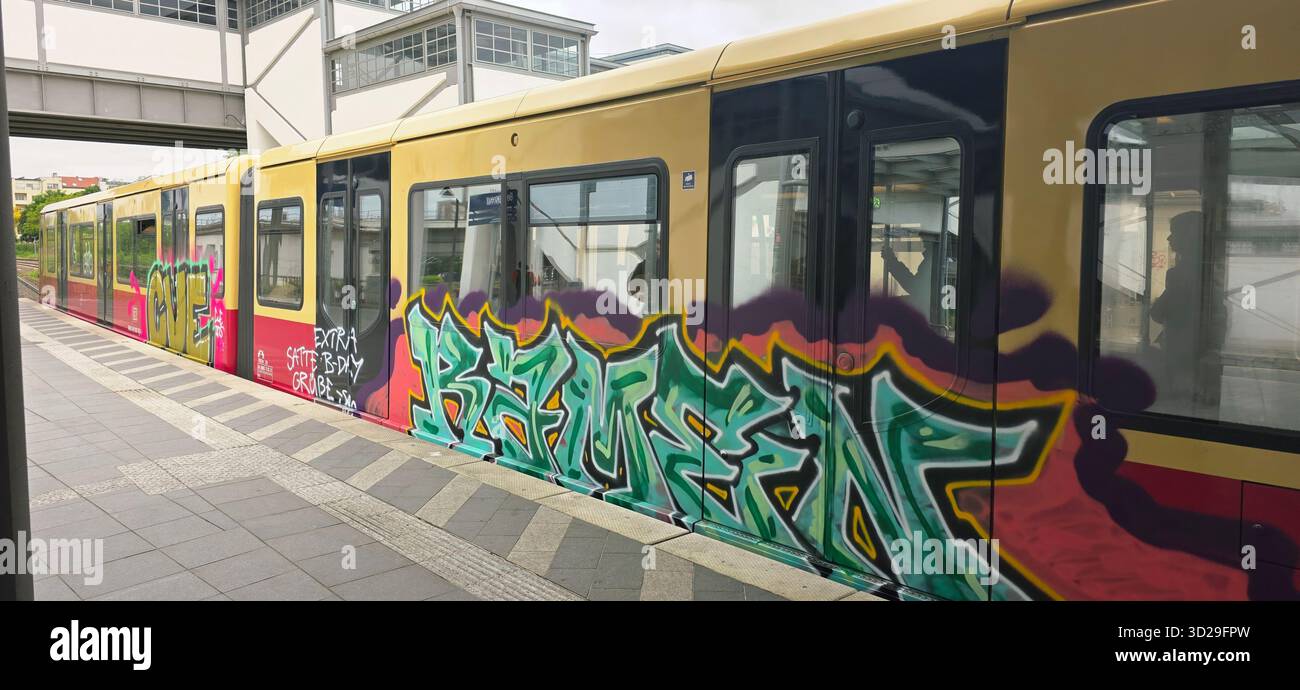 Belin, Deutschland - 19. Mai 2025: Der mit Graffiti bedeckte Zug parkt am Stadtbahnhof und bietet lebendige Street Art und Stadtatmosphäre. - Smartphone-aufgenommenes Stockfoto