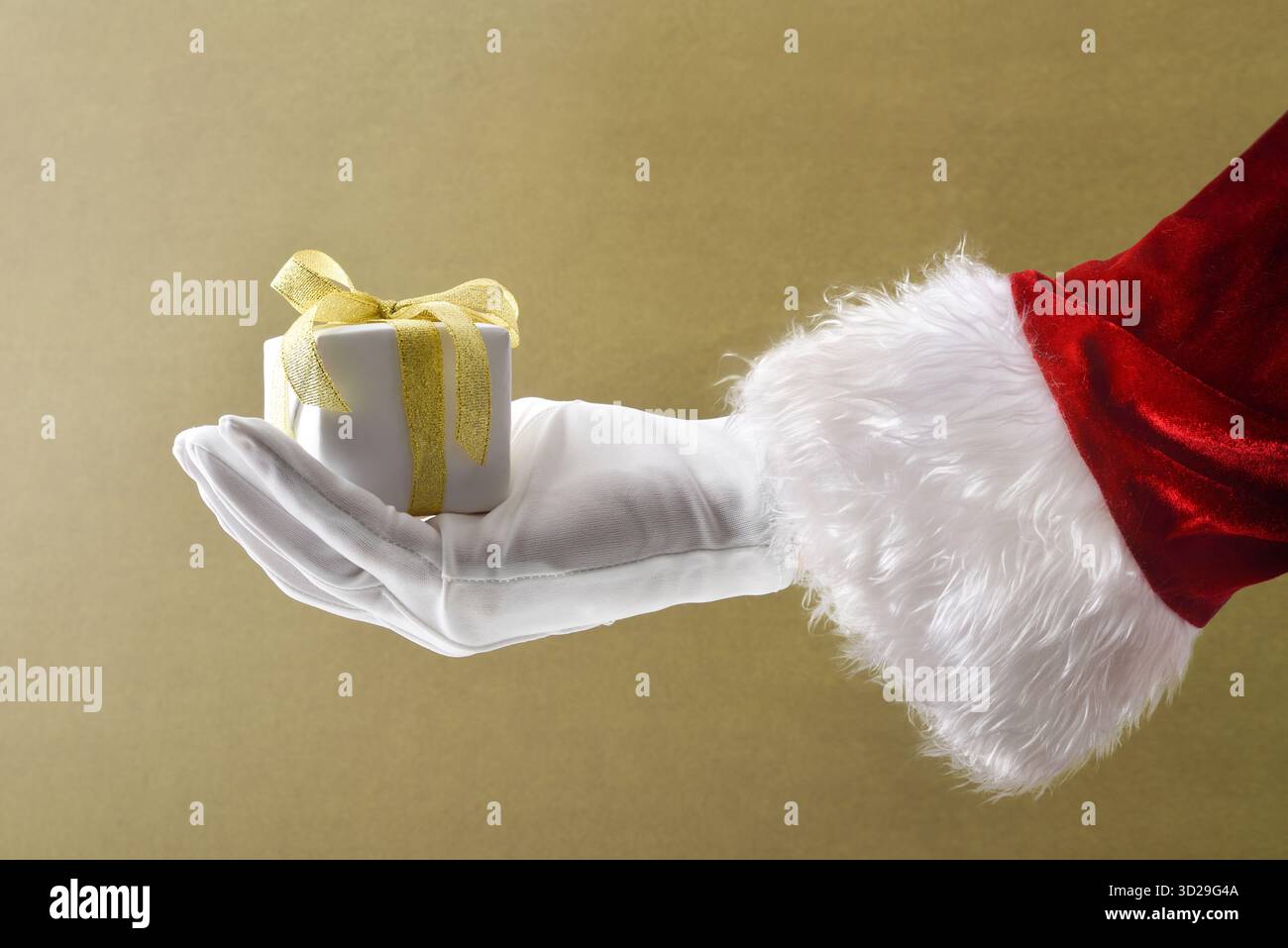 Weihnachtsmann Hand in Anzug und Handschuhe Geschenkpaket mit weißem Papier und goldener Schleife auf braun isoliertem Hintergrund. Stockfoto
