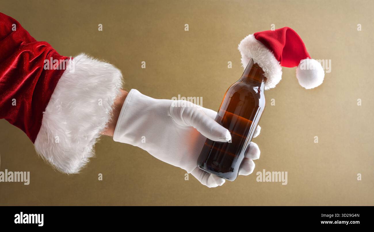 Weihnachtsmann Hand in Anzug und Handschuh mit Flasche Bier in der Hand dekoriert mit Weihnachtsmann Hut mit isoliertem Hintergrund Stockfoto