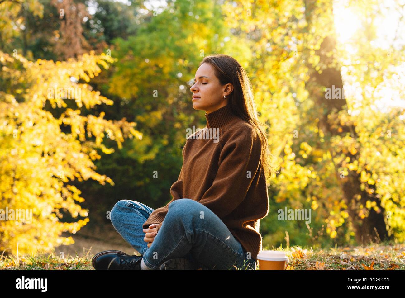 Ruhige Frau in Meditation posiert draußen im Herbst-Naturpark. Verbinden Sie sich wieder mit der Natur. Stockfoto