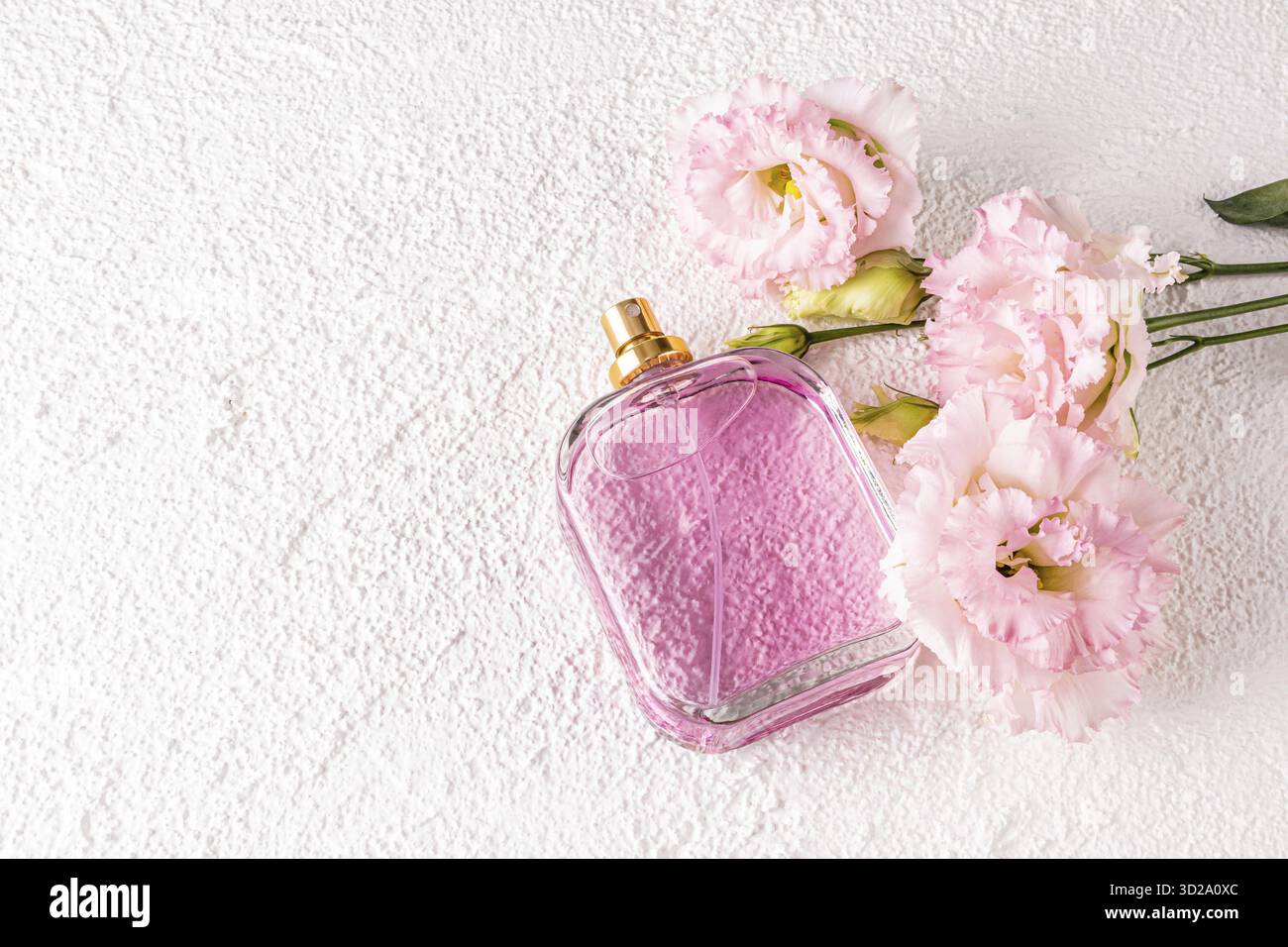 Elegante Flasche Damenparfüm mit zarten Düften auf weißem Hintergrund mit rosa Blüten. Leere Verpackung. Präsentation Stockfoto