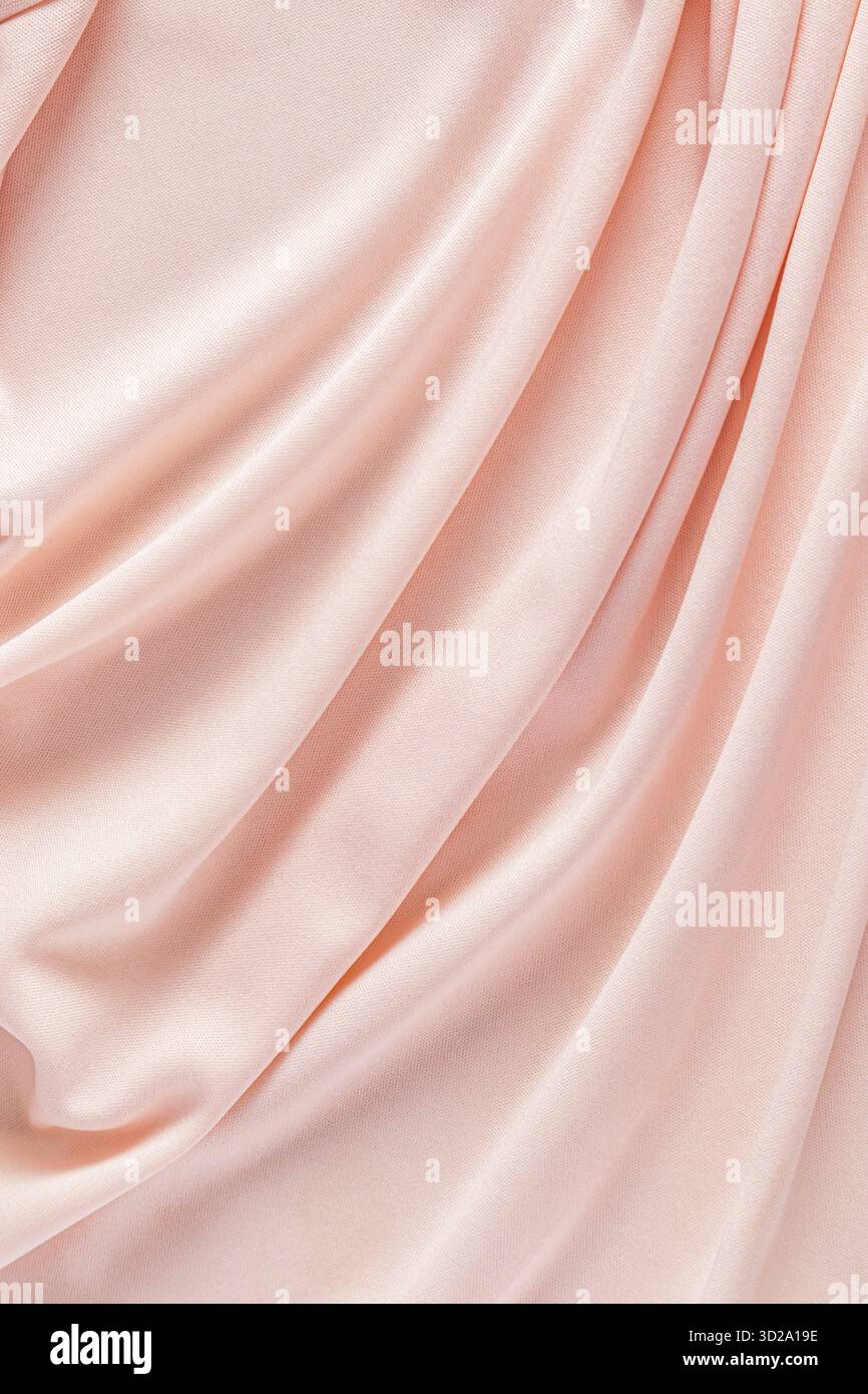 Luxuriöse Urlaubstextilien. Zarter Hintergrund aus Satin. Weiche Wellen aus pfirsichfarbenem Satin. Farbe des Jahres 2024 Peach Flusen. Vertikale Ansicht Stockfoto