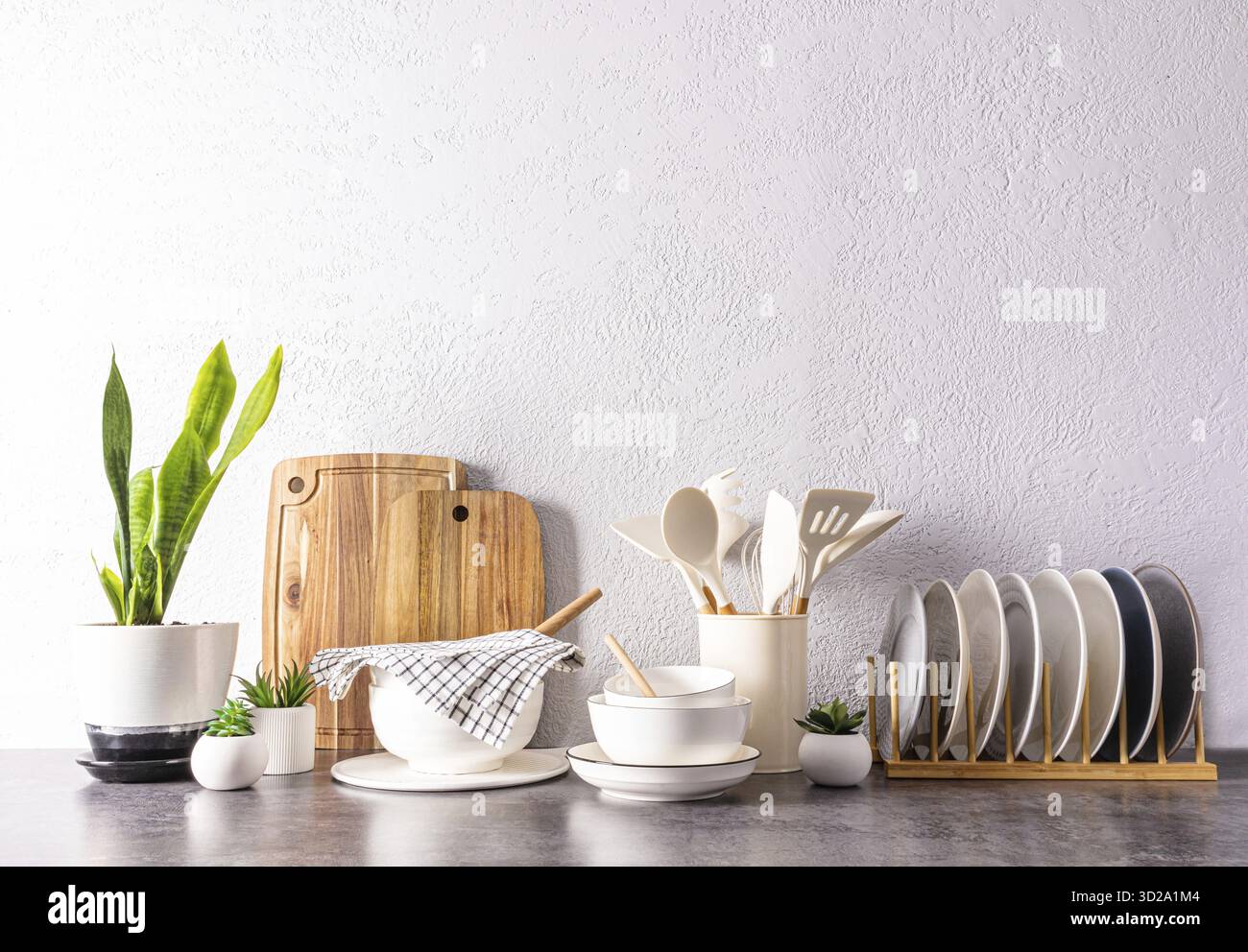 Ein Set verschiedener Küchenutensilien und -Werkzeuge, Keramikgeschirr in hellen Farben auf einer modernen Küchenarbeitsfläche. Vorderansicht. Ein Kopierbereich Stockfoto