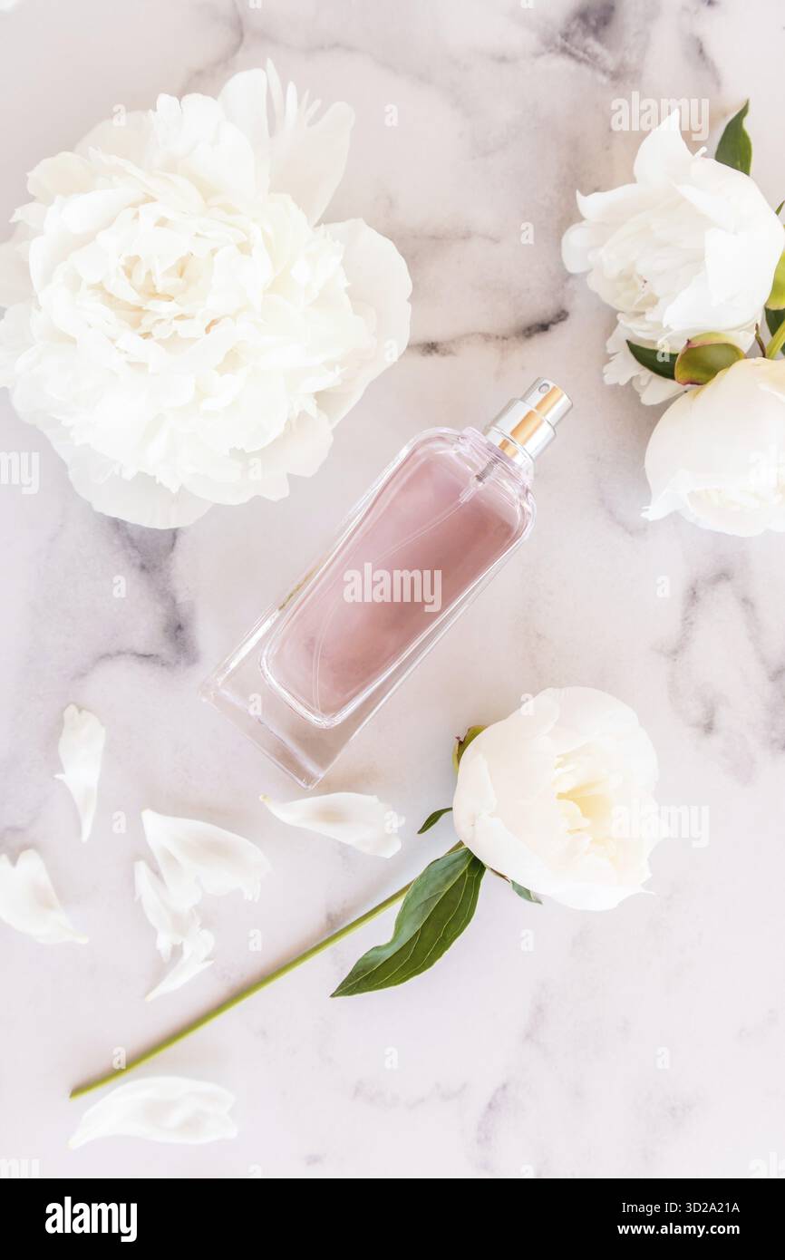 Duft von Damenparfüm oder -Spray. Vertikale Ansicht von oben auf eine elegante Parfümflasche mit weißen Pfingstrosen Stockfoto