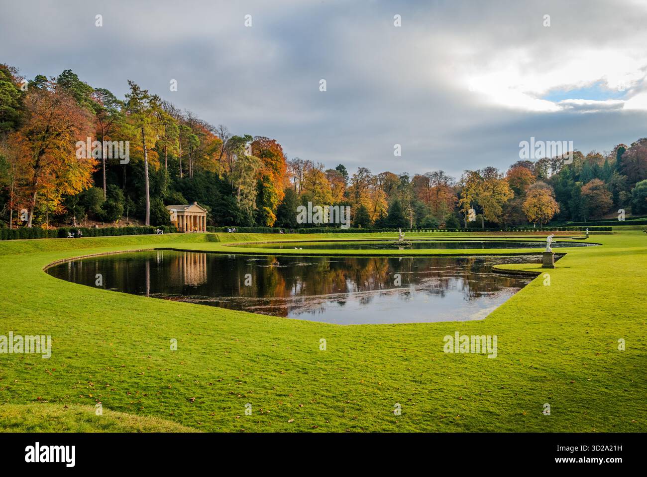 Überblick über den Studley Royal Water Garden im Herbst, mit Bäumen und Wasser, die warme Herbstfarben unter weichem, saisonalem Licht reflektieren Stockfoto