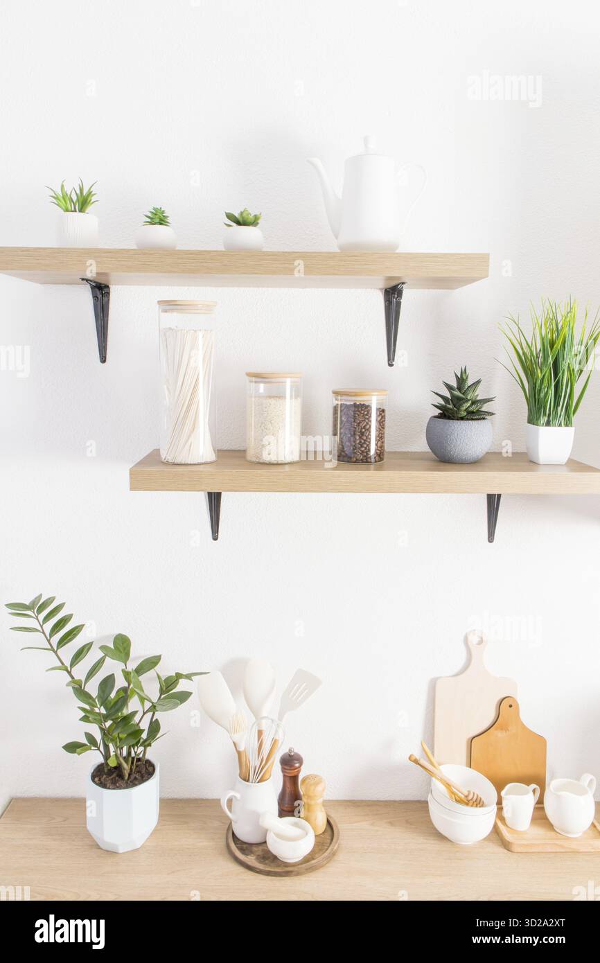 Vorderansicht der modernen Küche offene Regale mit Gläsern für die Lagerung von Lebensmitteln und Topfpflanzen. Teil der Arbeitsplatte mit Küchenutensilien Stockfoto