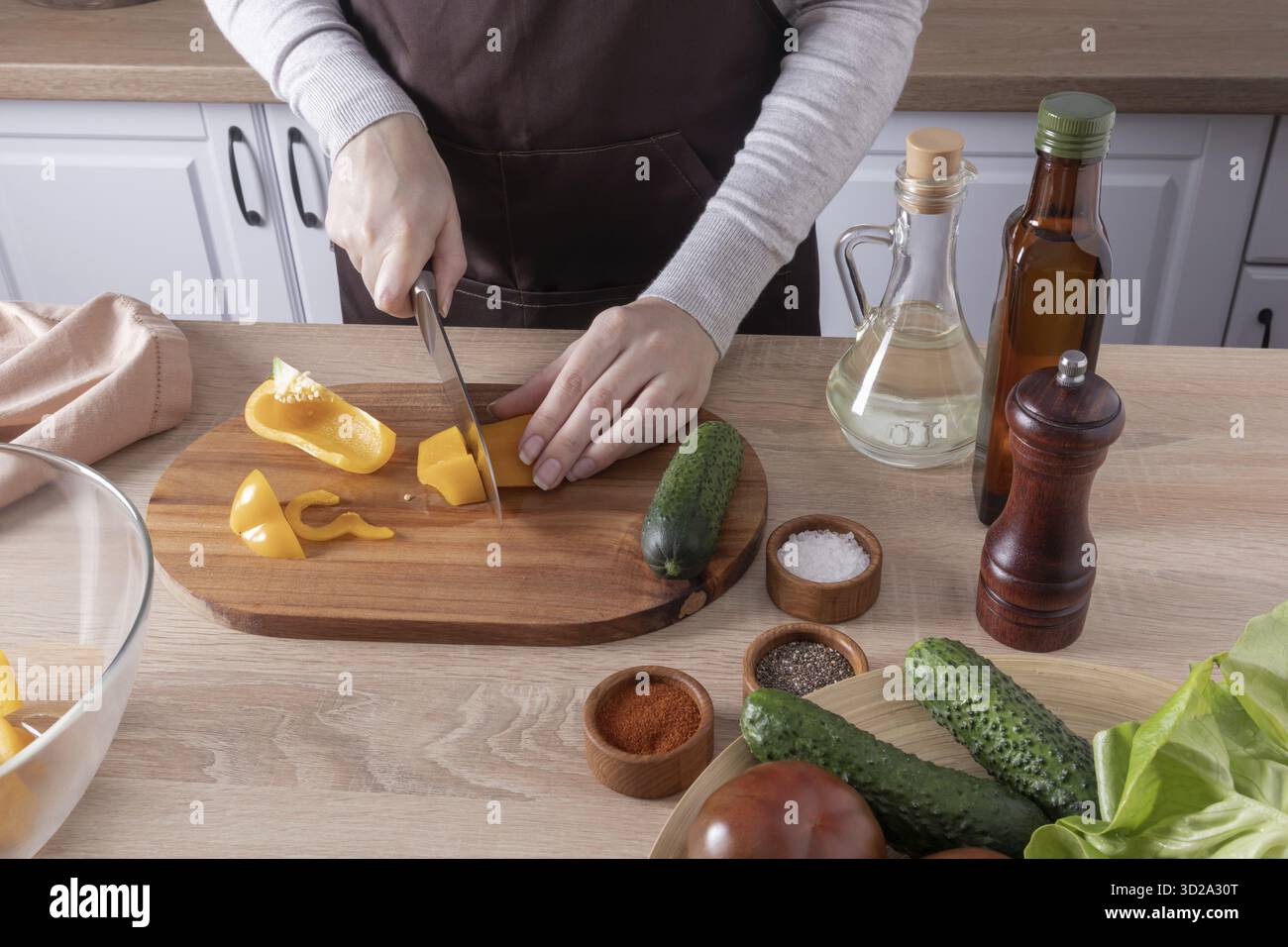 Kochen Sie köstliche gesunde vegetarische Speisen in der Küche zu Hause. Die Hände des Mädchens schneiden frische Paprika auf einem Schneidebrett Stockfoto