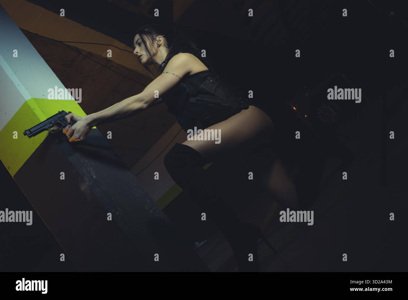 Militärische Brünette Mädchen mit Pistole in einer Garage in Haltung zu schießen, gekleidet in kugelsichere Weste Stockfoto