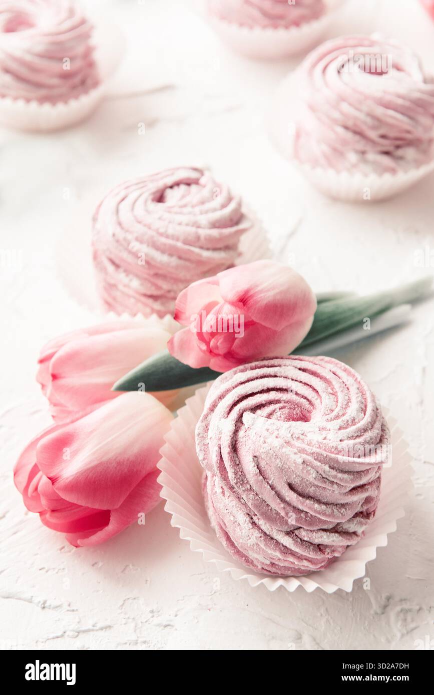 Marshmallows und pinkfarbene Blumen Tulpen auf weißem Hintergrund. Nahaufnahme Stockfoto
