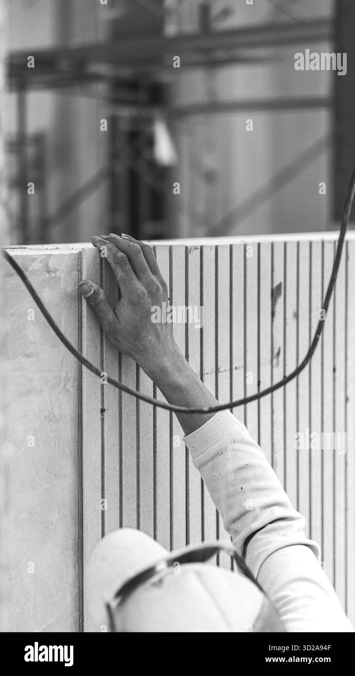 Bauarbeiter, der Conwood Wandpaneele installiert, um ein natürliches und ästhetisches Erscheinungsbild in einem modernen Gebäude zu schaffen. Stockfoto